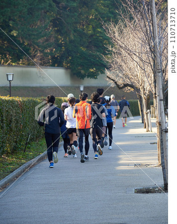冬の東京都の皇居外苑の道で走るランナーたちの姿 110713710