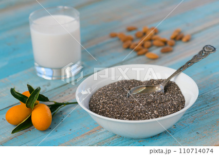 chia seeds in a plate and almond milk in a glass on a blue wooden background 110714074