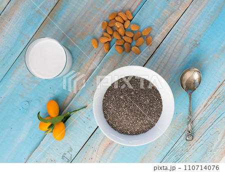 chia seeds in a plate and almond milk in a glass on a blue wooden background 110714076