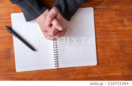 ノートの上で手を組む人 110715264