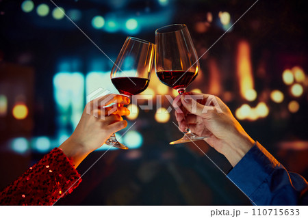 Valentine's Day special promotion at a boutique hotel. Male and female hands clinking glasses with red wine. Anniversary celebration Valentine's Day special promotion at a boutique hotel. Male and female hands clinking glasses with red wine. Anniversary celebration 110715633
