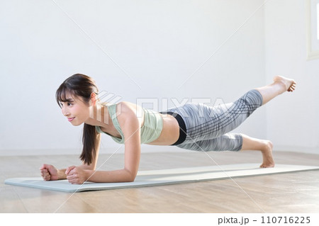 片足をあげたプランクで体幹を鍛える女性 110716225