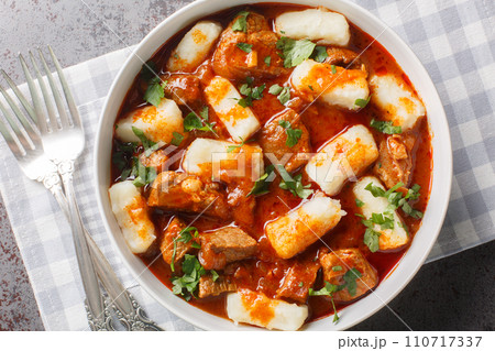 Potato dumplings or kopytka is made with cooked mashed potatoes served meat gravy close-up in a plate. Horizontal top view 110717337