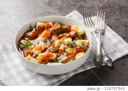 Kopytka Polish dumplings or little hooves made of mashed potatoes served with meat with gravy close-up in a plate. Horizontal 110717341