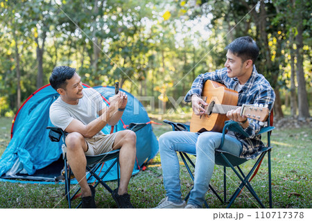 Happy Asian male gay couple on camping together in a forest. romantic vocation trip. lgbt concept Happy Asian male gay couple on camping together in a forest. romantic vocation trip. lgbt concept 110717378