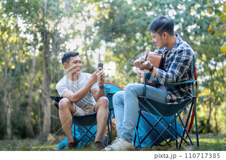 Happy Asian male gay couple on camping together in a forest. romantic vocation trip. lgbt concept Happy Asian male gay couple on camping together in a forest. romantic vocation trip. lgbt concept 110717385