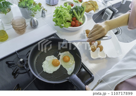 キッチンで目玉焼きを作る若い女性の手元 キッチンで目玉焼きを作る若い女性の手元 110717899