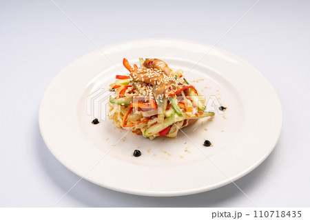 Dinner. Traditional Asian salad with chicken in sweet and sour sauce on a white plate and a white background. Dinner. Traditional Asian salad with chicken in sweet and sour sauce on a white plate and a white background. 110718435