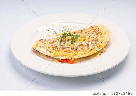 Breakfast. Omelet with vegetables and cheese on a white plate and a white background. Breakfast. Omelet with vegetables and cheese on a white plate and a white background. 110718460