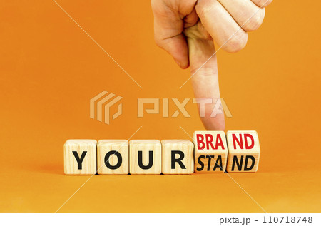 Branding your brand or stand symbol. Concept words Your stand Your brand on beautiful blocks. Beautiful orange background. Businessman hand. Business branding your brand or stand concept. Copy space. Branding your brand or stand symbol. Concept words Your stand Your brand on beautiful blocks. Beautiful orange background. Businessman hand. Business branding your brand or stand concept. Copy space. 110718748