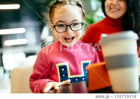 Happy family moments concept. Happy child girl in eyeglasses laughing at camera in cafe indoor. Mother and daughter spend time at coffee shop. 110719158
