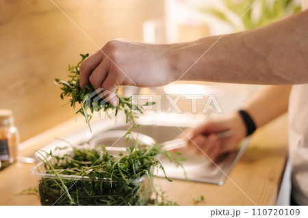 Side view of human hand take a bunch of arugula and rinses with water Side view of human hand take a bunch of arugula and rinses with water 110720109