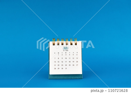 July 2024 mini desk calendar on blue background. 110721628