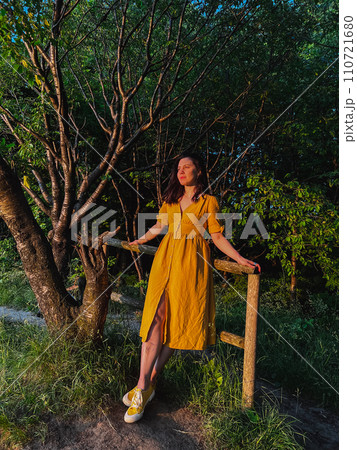 A woman stands by the fence at sunset 110721680