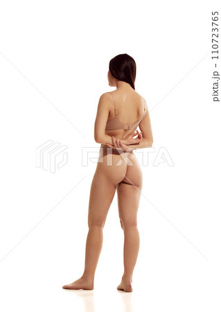 Full length portrait of young woman with perfect curves, without cellulite posing in beige lingerie against white studio background. 110723765