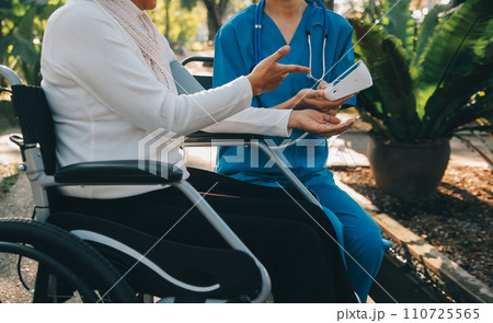 nurse with elderly man in wheelchair at park 110725565