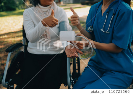 nurse with elderly man in wheelchair at park 110725566