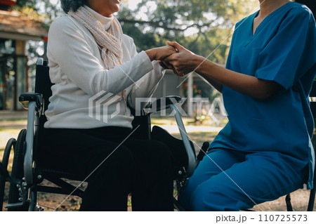 A nurse take care a senior male on wheelchair in his garden at home A nurse take care a senior male on wheelchair in his garden at home 110725573