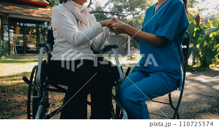 A nurse take care a senior male on wheelchair in his garden at home A nurse take care a senior male on wheelchair in his garden at home 110725574