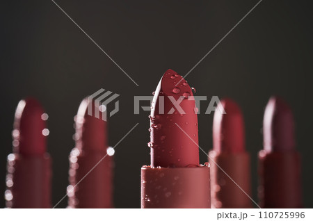Red lipsticks with water drops on a dark background. Red lipsticks with water drops on a dark background. 110725996