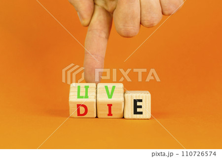 Live or die symbol. Concept word Live or Die on wooden cubes. Beautiful orange table orange background. Businessman hand. Business lifestyle and live or die concept. Copy space. Live or die symbol. Concept word Live or Die on wooden cubes. Beautiful orange table orange background. Businessman hand. Business lifestyle and live or die concept. Copy space. 110726574