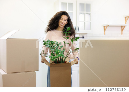 happy young African American woman is moving into new home. person stands among cardboard boxes  110728139