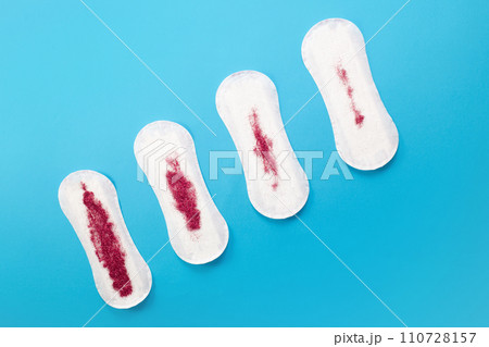 Feminine hygiene pads with red glitter on blue background. First menstrual period concept Feminine hygiene pads with red glitter on blue background. First menstrual period concept 110728157