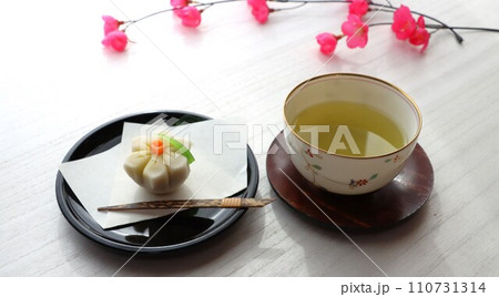 黒塗りの丸皿にのった水仙の花を模した上品な和菓子と緑茶 黒塗りの丸皿にのった水仙の花を模した上品な和菓子と緑茶 110731314
