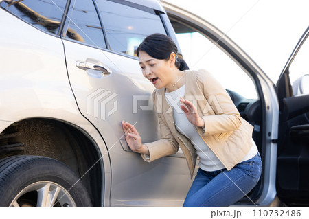 車をぶつけてショックを受ける女性 110732486
