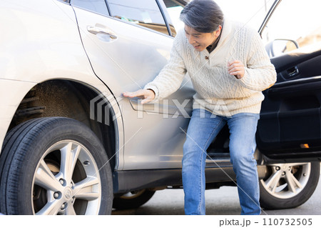 車をぶつけてショックを受ける男性 110732505