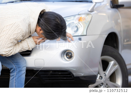 車をぶつけてショックを受ける男性 110732512