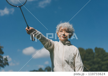 屋外でバドミントンをする60代女性 屋外でバドミントンをする60代女性 110733624