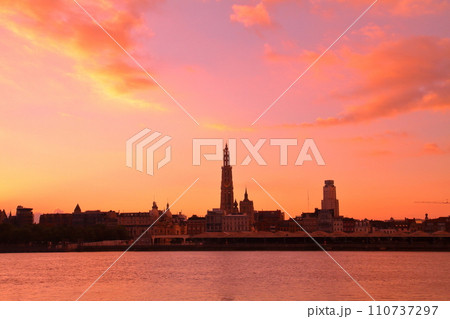 西ヨーロッパのベルギー アントワープを流れるエスコー川の対岸から朝焼けの市街地のシルエット 110737297