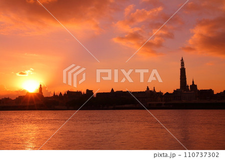 西ヨーロッパのベルギー アントワープを流れるエスコー川の対岸から朝焼けの市街地のシルエット 110737302