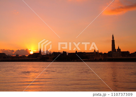 西ヨーロッパのベルギー アントワープを流れるエスコー川の対岸から朝焼けの市街地のシルエット 西ヨーロッパのベルギー アントワープを流れるエスコー川の対岸から朝焼けの市街地のシルエット 110737309