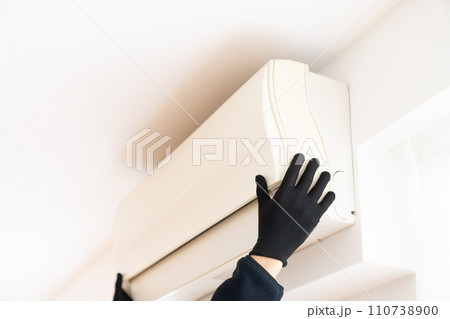 エアコンを取り外す黒い作業用手袋をはめた手元 110738900