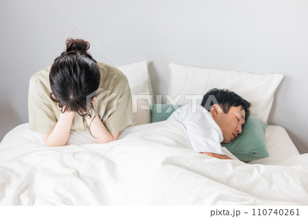 ベッドの上で睡眠不足に悩む女性と眠る男性(不眠症・ストレス・安眠妨害) ベッドの上で睡眠不足に悩む女性と眠る男性(不眠症・ストレス・安眠妨害) 110740261