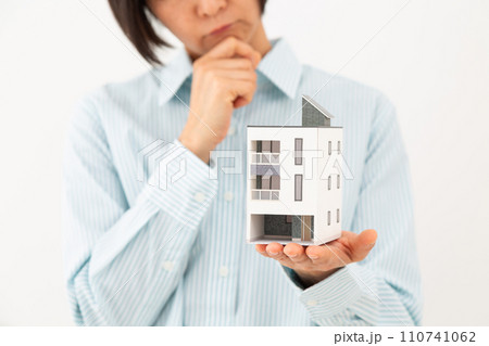 戸建ての住宅模型を持って悩むミドル女性 110741062