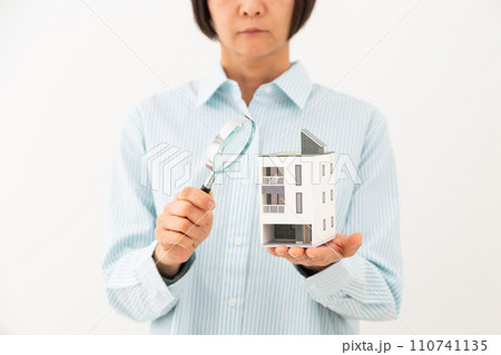 戸建ての住宅模型とルーペを持つミドル女性 110741135