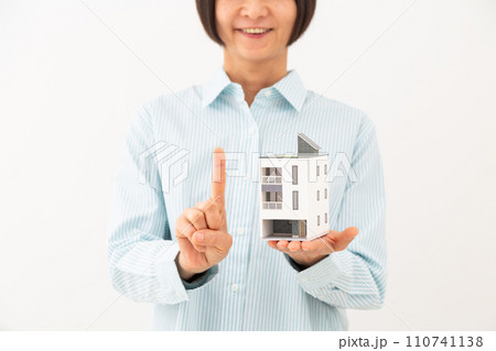戸建ての住宅模型を持って人差し指を立てるミドル女性 戸建ての住宅模型を持って人差し指を立てるミドル女性 110741138