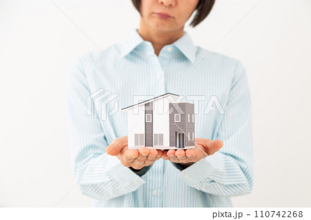 戸建ての住宅模型を持って悩むミドル女性 110742268