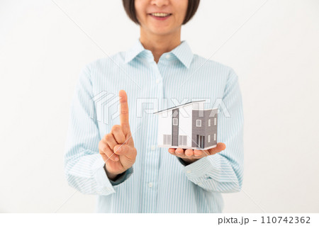 戸建ての住宅模型を持って人差し指を立てるミドル女性 戸建ての住宅模型を持って人差し指を立てるミドル女性 110742362