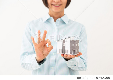 戸建ての住宅模型を持って丸サインをするミドル女性 110742366