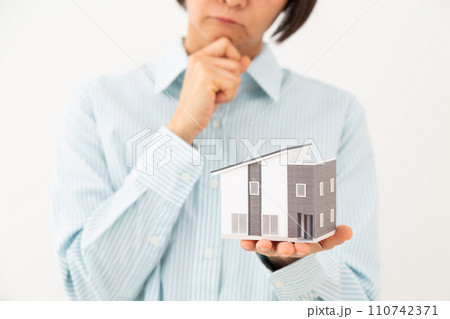 戸建ての住宅模型を持って悩むミドル女性 110742371