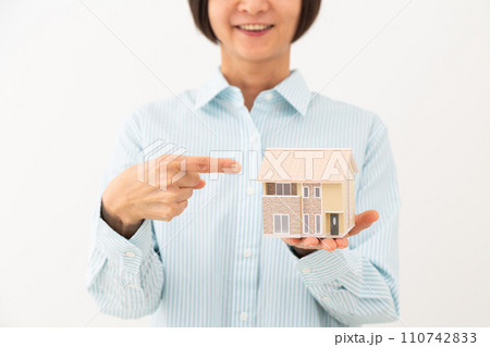 戸建ての住宅模型を指差して笑うミドル女性 110742833