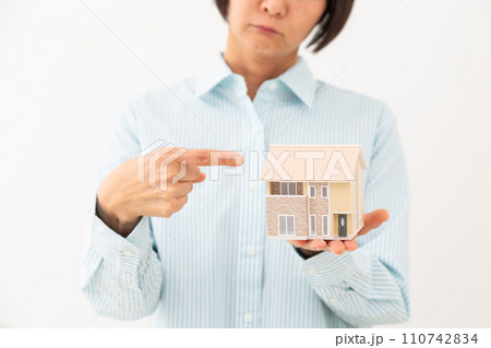 戸建ての住宅模型を指差して悩むミドル女性 110742834