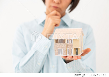 戸建ての住宅模型を持って悩むミドル女性 110742836
