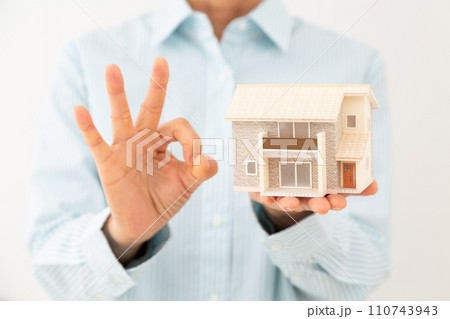 戸建ての住宅模型を持って丸サインをするミドル女性 110743943