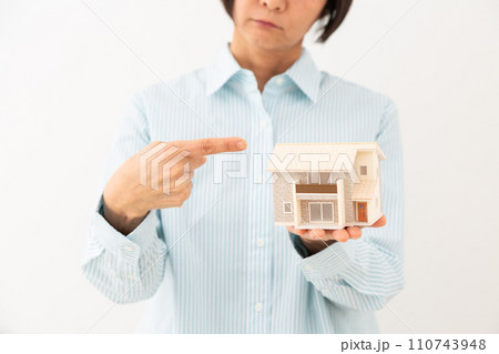 戸建ての住宅模型を指差して悩むミドル女性 110743948
