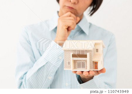 戸建ての住宅模型を持って悩むミドル女性 110743949